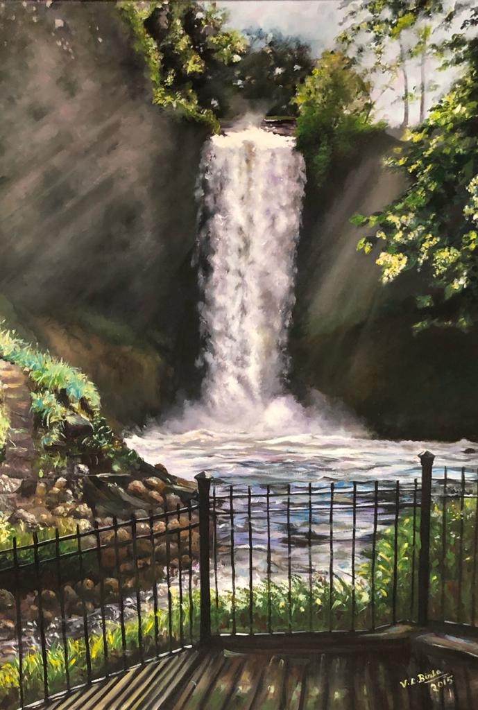 Sunlit waterfall pouring into a river beyond a garden railing