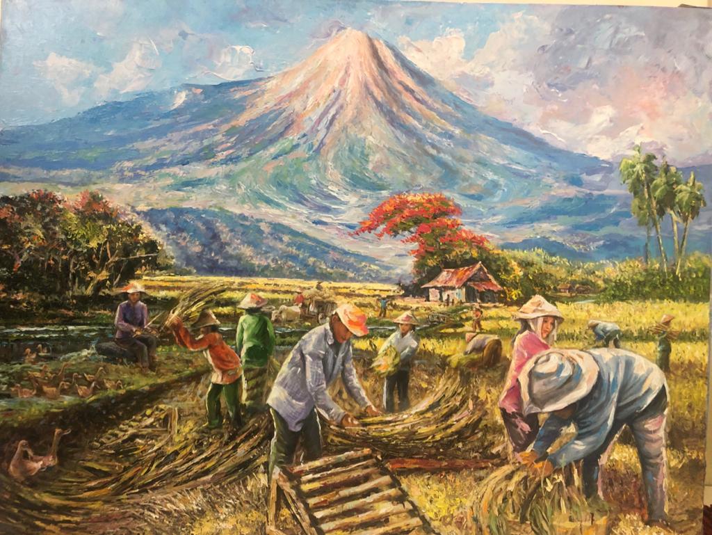 Farmers harvesting rice in Java with a volcano behind them