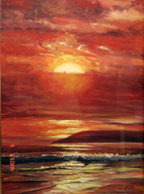 Boats sailing across the ocean beneath a fiery red-orange sunrise